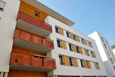 Volets bois coulissants épurés à la teinte ensoleillée sur façades en béton brut
