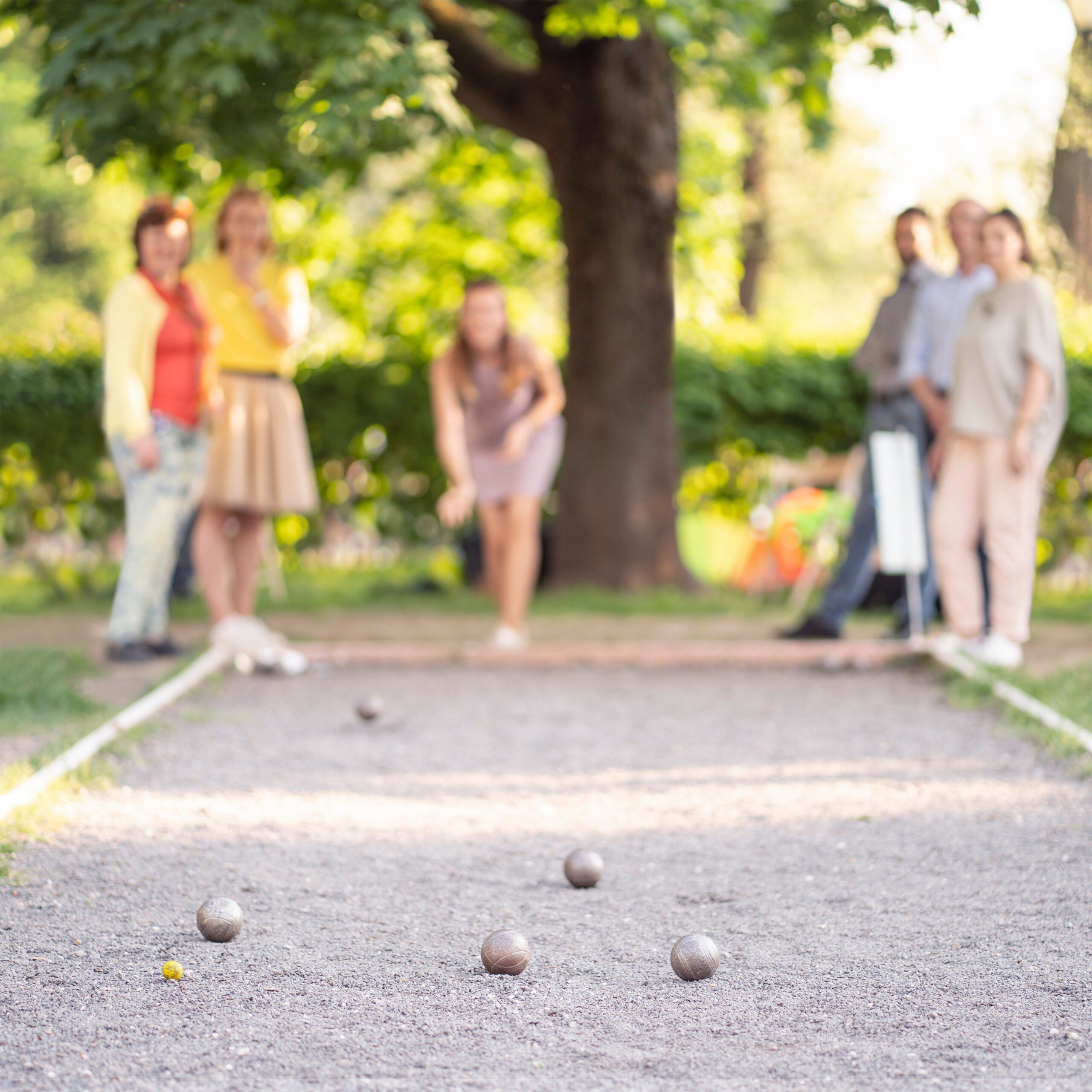 Friends playing petanque woman throwing a ball outdoor city park rse gpf