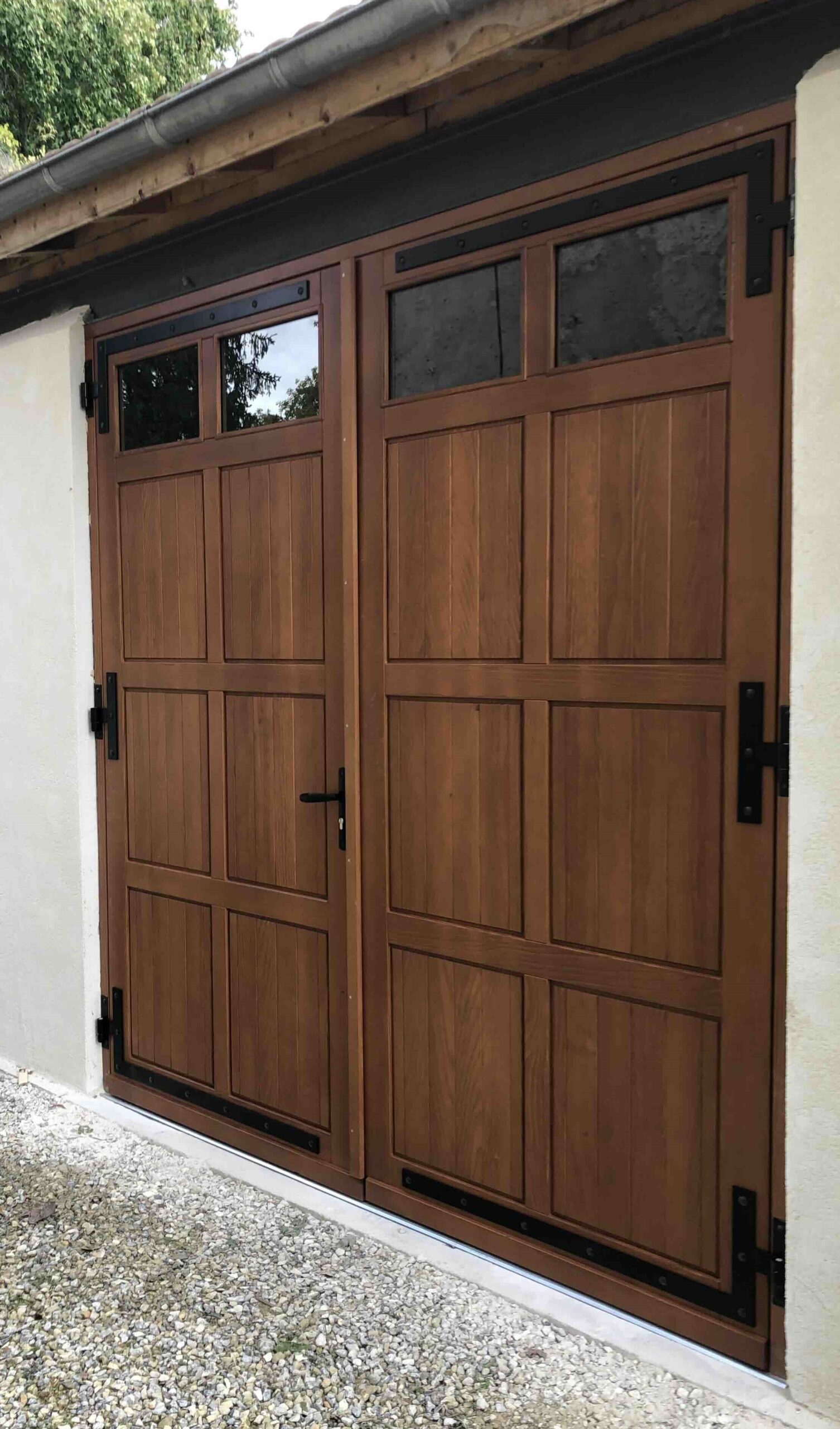 Porte de garage battante à la française en bois Douglas finition chêne doré avec oculus vitrés et ferrage noir