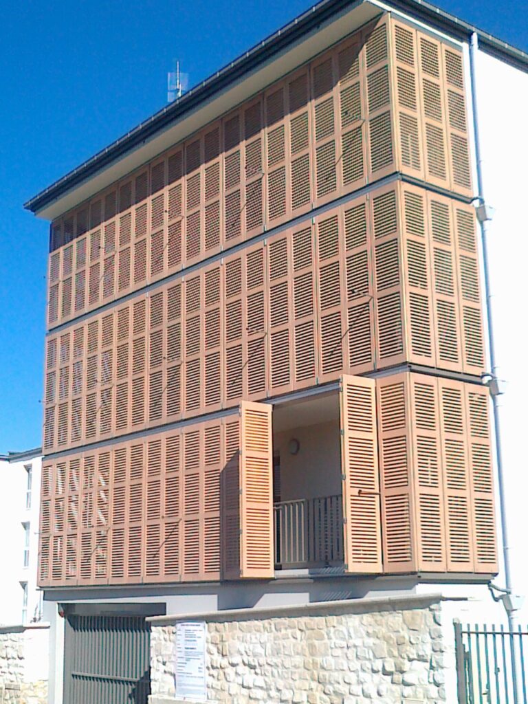 Façade contemporaine équipée de volets coulissants pliants en persienne bois pour le confort d'été