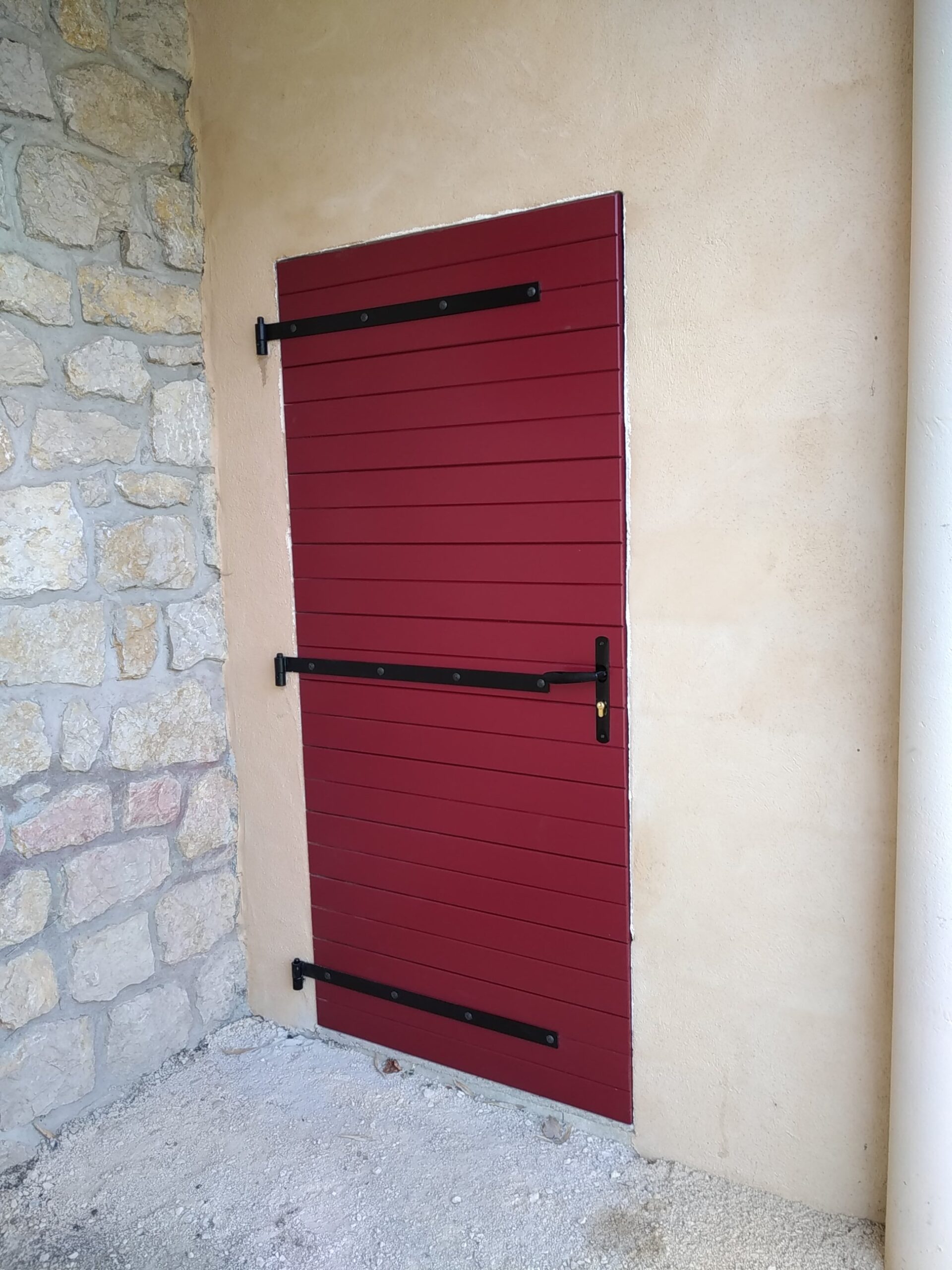 Porte de garage Vieille France PGVF59 un vantail laque Rouge Pourpre RAL 3004, frises horizontales, façade pierre et enduit